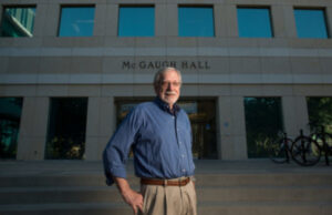 UCI neuroscientist and founding faculty member James McGaugh stands in front of the campus building that is named after him.
