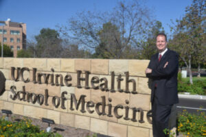 Theo van Erp stands in front of the Uci School of Medicine Sign