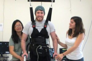 A man whose legs had been paralyzed for five years walks along a 12-foot course using UCI-developed technology that lets the brain bypass the spinal cord to send messages to the legs. Courtesy of UCI’s Brain Computer Interface Lab