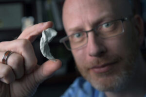 Craig Stark Ph.D. holds a piece of clay up to the camera