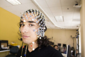 UCI doctoral candidate Sumner Norman wears an EEG cap that figures prominently in his robotics research to help stroke victims.