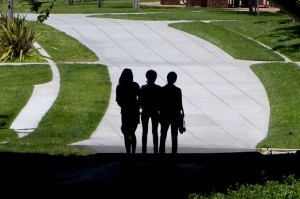 3 silhouettes walk on a concrete path