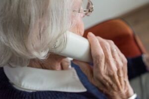 An elderly woman holds phone to her ear