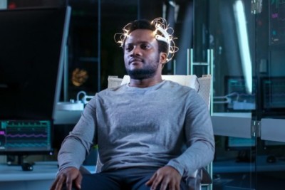 Image of a person sitting in a chair with brainscan devices on his head