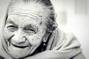 An elderly woman sends a toothless smile at the camera