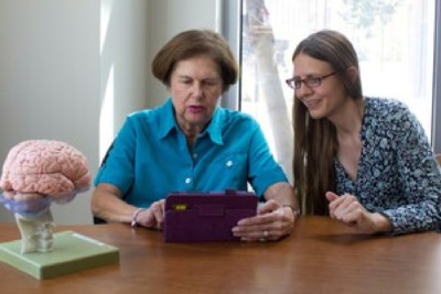Susanne Jaeggi sits beside a older female participant holding a tablet.