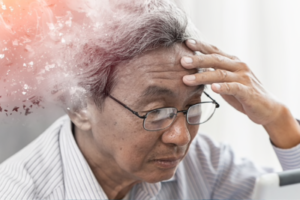 Image of an older Asian male holding their forhead.