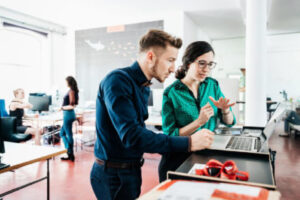 Image of coworkers collaborating on a laptop in an office setting.