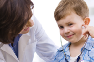 Image of a female doctor smiling at a pediatric patient holding a stethoscope.