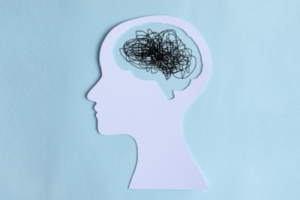 Abstract image of a paper cutout of a silhouette of an individual with pen scribbles outlining the brain.