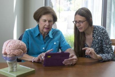 Dr Susanne M. Jaeggi sits beside a woman holding a tablet device.
