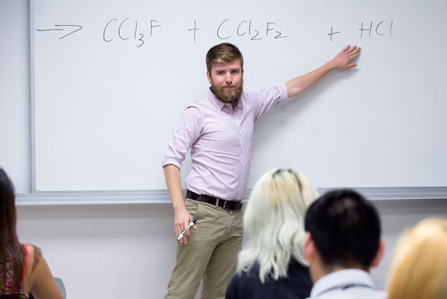 Candid photo of male explaining a chemical formula in an educational setting