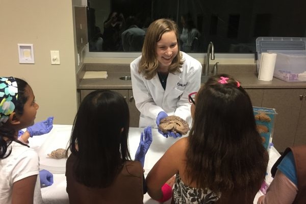 Female researcher displays a brain to a group of students