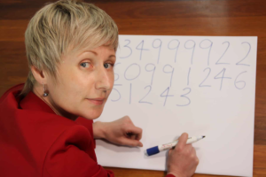 Headshot of Anastasia Woolmer writing numbers down on paper