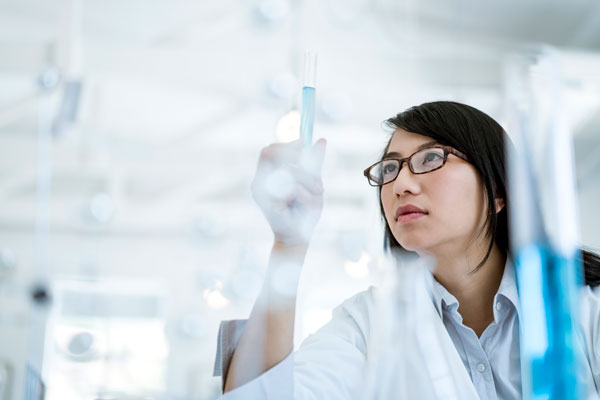 Stock image of a female researcher viewing a sample.