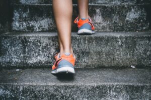Image of individual wearing sneakers stepping up the stairs.
