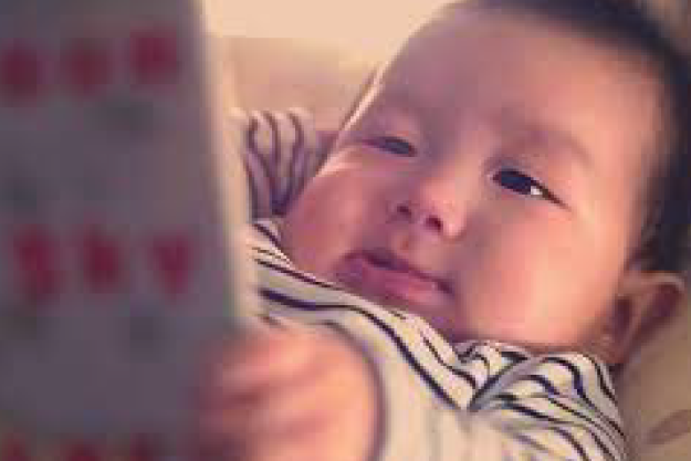 A baby stares at what seems to be an iPad screen