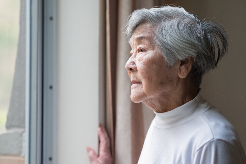 An elderly woman stares out the window