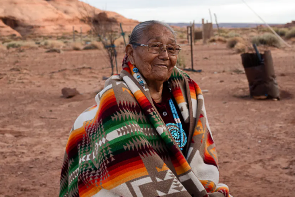 An elderly Native woman smiles at the camera