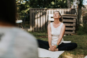 A woman sits on the floor with closed eyes and her feet pressed together in a meditative pose