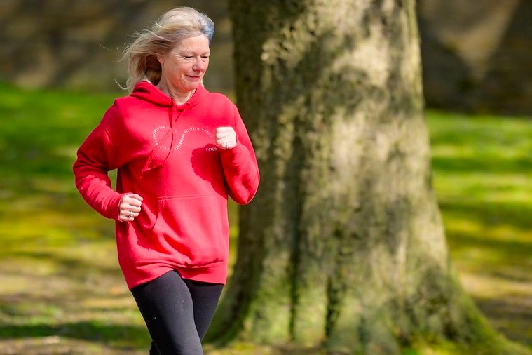 Image of an elderly lady jogging wearing a bright red sweater.