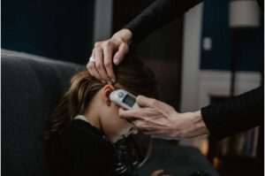 A child has a medical device being held up to her ear