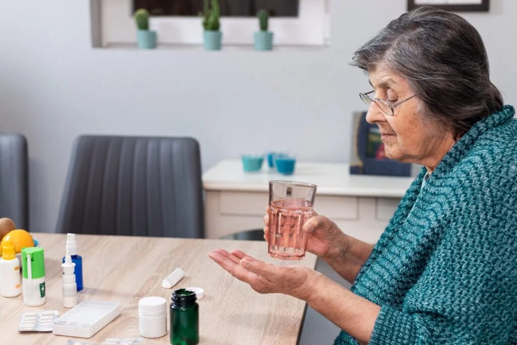 Elderly woman takes pill with water