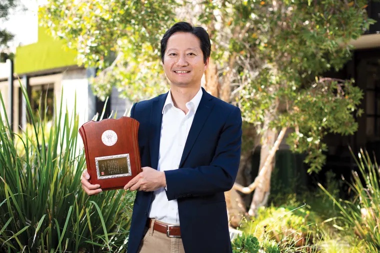 Associate professor Kei Igarashi holding award - Person of Interest- UC Irvine professor honored for Alzheimer’s research